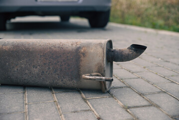 the rusty exhaust pipe, the car's muffler has fallen off and is lying on the road