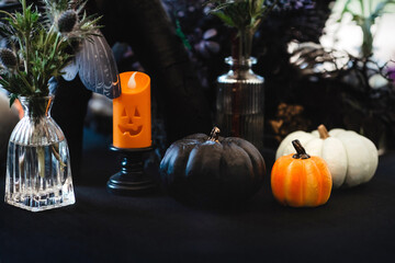 Autumn composition with three pumpkins and a candle in dark colours. The theme of the holiday Halloween.