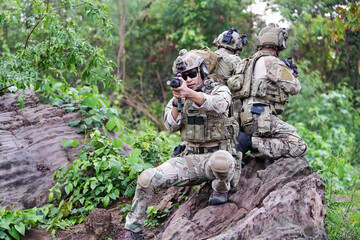 Military army soldiers tactical team, commando group moving cautiously in forest area, kneeling and looking around, covering comrades, controlling sectors. Commander showing halt or stop hand signal