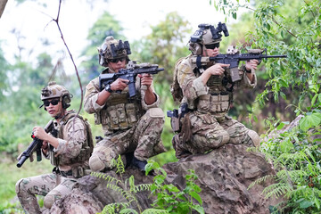 Military army soldiers tactical team, commando group moving cautiously in forest area, kneeling and...