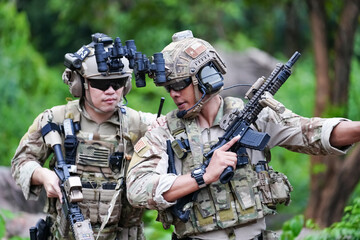 Military army soldiers tactical team, commando group moving cautiously in forest area, kneeling and looking around, covering comrades, controlling sectors. Commander showing halt or stop hand signal