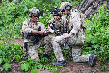 Military army soldiers tactical team, commando group moving cautiously in forest area, kneeling and looking around, covering comrades, controlling sectors. Commander showing halt or stop hand signal