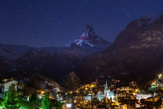 Settlement underneath mountain snowy peak with projector light show with United Kingdom flag
