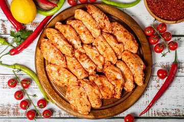 Chicken wings with sauce on wood background. Raw chicken wings with herbs and spices