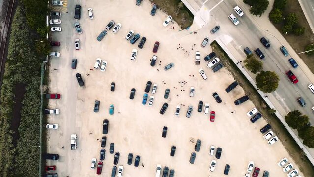 A Top Down Creative Tracking Cinematic Drone 4K Long Take Aerial Shot of Small People Ants Crowd Control Leaving Shaw Park in Winnipeg Manitoba Walking on a Gravel Dirt Parking Lot Colorful Cars