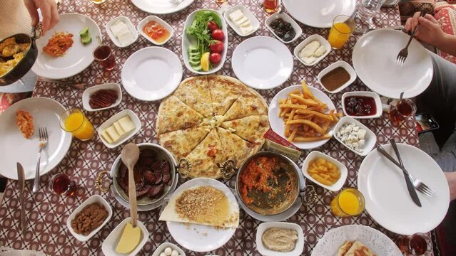 Traditional Turkish village breakfast on the wooden table with variety of food. Hands taking food from different plates.