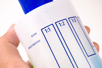 Close up a dilution ratio label of concentrated liquid chemicals on plastic bottles, human hand...
