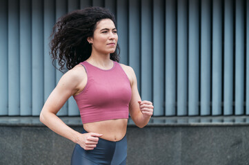 Portrait of young woman running outside. Jogging in city