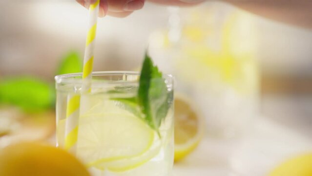 A housewife parent adds a straw to a prepared cocktail in the kitchen of a private home. Camera in motion, a European woman adds a paper straw to the finished mojito lemonade, applies cutlery, fresh