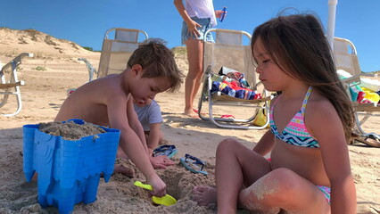 Children at the beach playing with sand, kids making sand castle during summer vacations