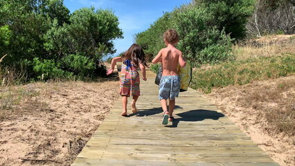 Children going to the beach on wooden pathway