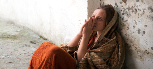 A girl in poor clothes sits on the ground