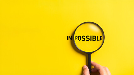 Hand holding magnifying glass with possible and impossible words on the yellow background. Optimistic and Business metaphor concept. - obrazy, fototapety, plakaty