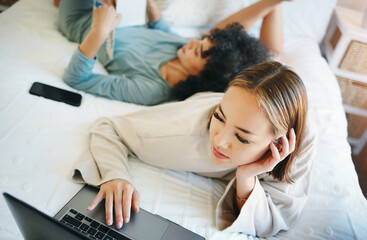 Obraz premium Laptop, morning and a lesbian couple relaxing in bed while together in their home on the weekend. Computer, search and online with lgbt woman with her girlfriend in the bedroom for love or bonding