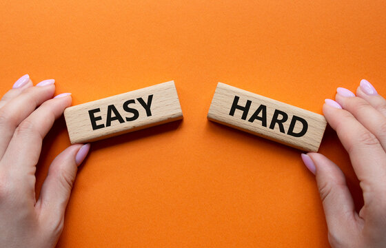 Easy or Hard symbol. Concept word Easy or Hard on wooden blocks. Businessman hand. Beautiful orange background. Business and Easy or Hard concept. Copy space