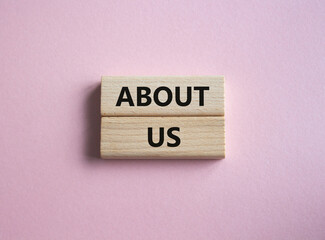 About us symbol. Concept word About us on wooden blocks. Beautiful pink background. Business and...