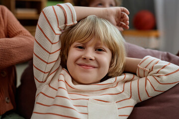 Closeup portrait of cute blonde boy smiling at camera while playing in preschool or kindergarten
