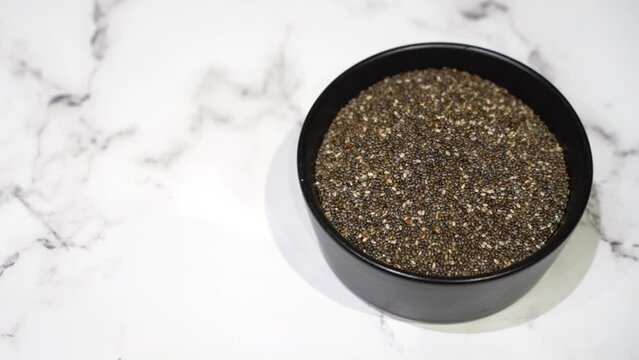 Chia Seeds in a Bowl on Marble Background. Chia seeds, a nutritional powerhouse, are featured in this image. Rich in omega-3 fatty acids, fiber, and protein, these tiny seeds support heart health