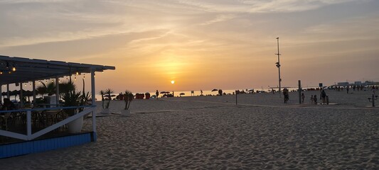 Sunset on the beach with silhouettes of people enjoying the view.