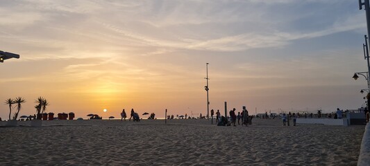 Sunset on the beach with silhouettes of people enjoying the view.