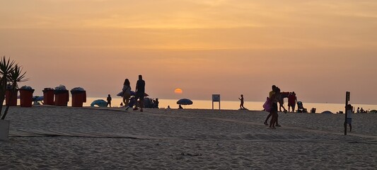 Sunset on the beach with silhouettes of people enjoying the view.