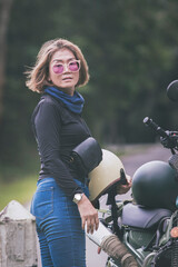 pretty woman holding safety helmet standing beside  small enduro motorcycle