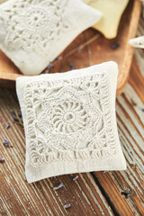 Sachet bags decorated with crocheted lace and lavender on a wooden background