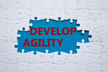 Develop agility symbol. Concept word Develop agility on white puzzle. Beautiful blue background....