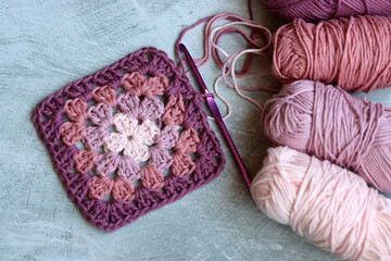 Granny square pattern made of soft organic cotton top view photo. Grey background with copy space. Spring crochet ideas. 