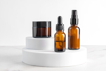 Set of beauty products in glass bottles on white podiums on white background. Skin care set for daily routine. Mockup for designers