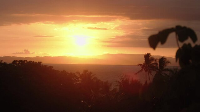 Static slow motion shot of an orange sunset from the jungle in Costa Rica. Wide shot overlooking the Pacific Ocean, with a highly contrasted sunset.