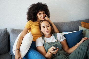 Love, relax and a gay couple watching tv on a sofa in the living room of their home together....