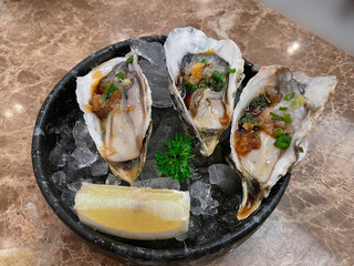 Fresh oysters with red with soy sauce served on ice.