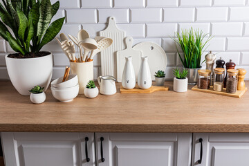 Beautiful kitchen background of a modern countertop with a set of various kitchen utensils, green plants in pots. Eco style. natural materials.