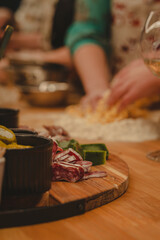 Wooden cutting board with sausage and cheese and pasta making on the background