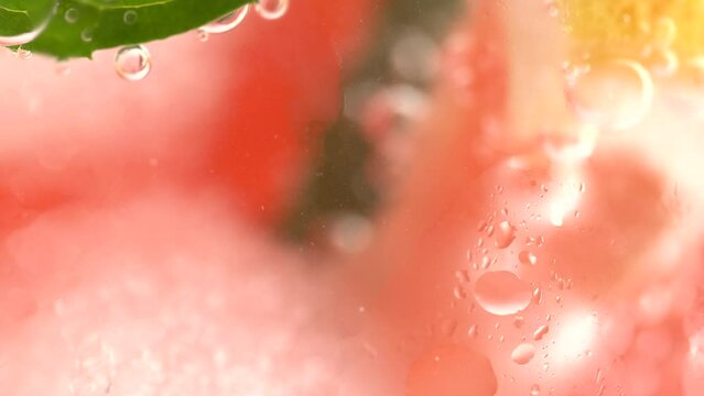 Fizzing water with grapefruit slices, mint and ice cubes in glass, macro. Healthy lifestyle concept
