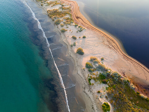 Aerial view of a narrow strip of beach with calm sea on both sides