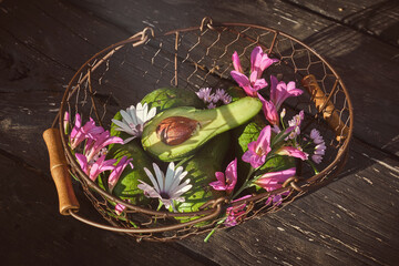Basket with flowers and avocado on table