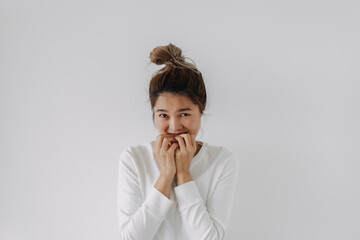 Happy cute asian Thai woman bun hair, shy embarrassing and ashamed, bite her two hands, look at camera, isolated on white background in winter.