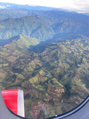 chaine de montagnes vue depuis le hublot d'un avion. Le paysage est vert et se situe dans la province de Medellin. 