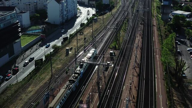 City passenger train is moving on the track near the city. Aerial shot