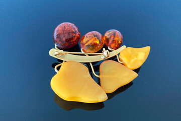 vintage brooch berries and leaves with of amber and brass, made in USSR on dark glossy background