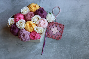 Bouquet made of cotton yarn balls  in a wooden box. Colorful photo of soft pink organic yarn. Hobbies and leisure concept. Light grey background with copy space. 