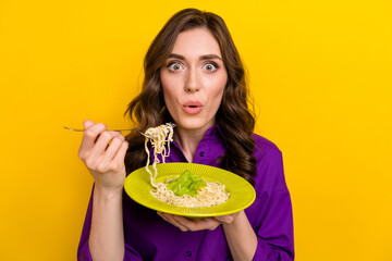 Photo of impressed pretty lady pouted lips arms hold noodle pasta fork isolated on yellow color...