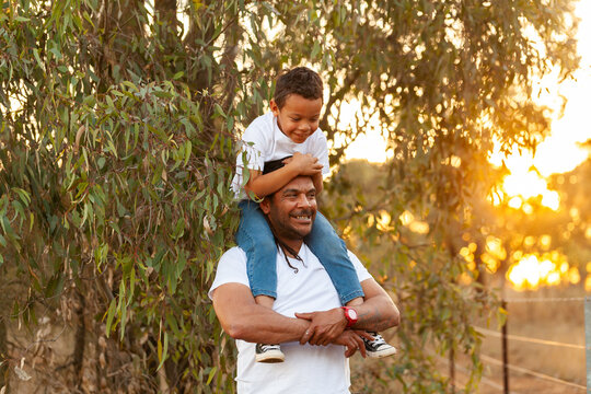 Happy father and son portrait standing by hanging leaves of australian eucalyptus tree