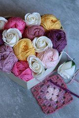Bouquet made of cotton yarn balls  in a wooden box. Colorful photo of soft pink organic yarn. Hobbies and leisure concept. Light grey background with copy space. 