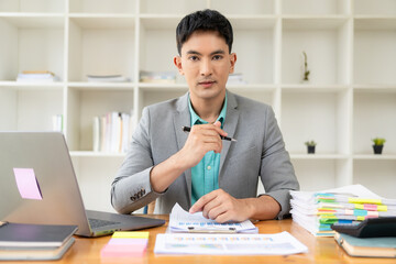 Asian businessman working at office with laptop and documents on table Work in the workplace, business documents, financial planning concepts