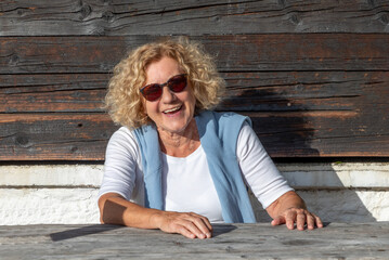 attractive senior laughing woman sitting at a rural table and enjoys life