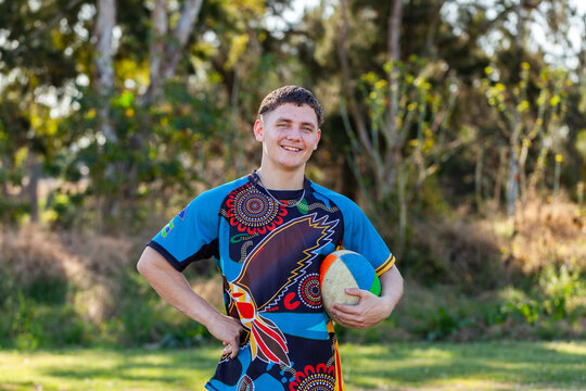 Smiling portrait of happy teenage Australian footy sports player holding football