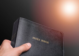 Young man holding bible book on sun light.